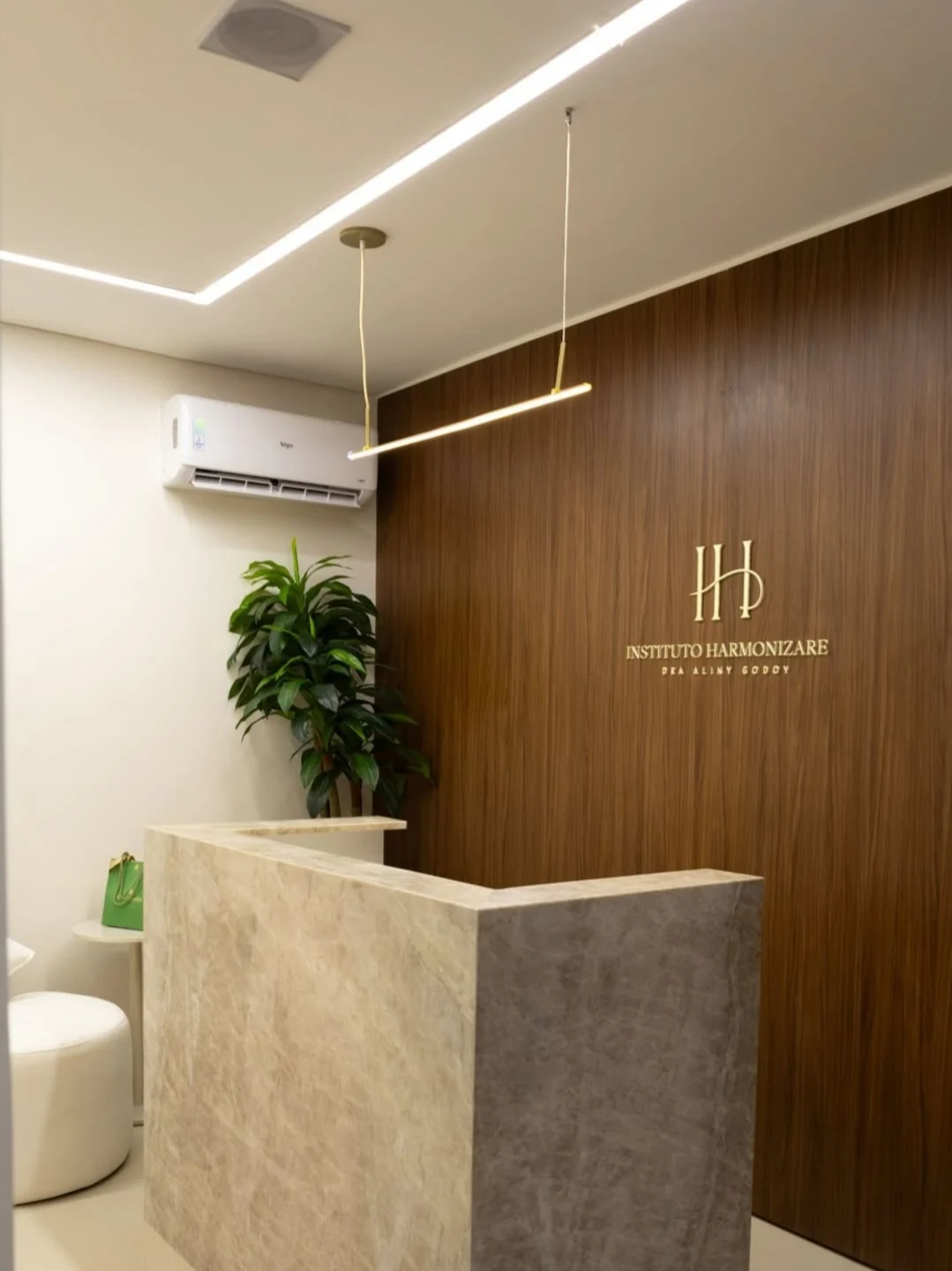 Recepção do Instituto Harmonizare, com o balcão de quartzito e o painel de nogueira