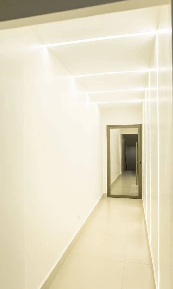 Corredor branco com linhas de luz no teto e na parede